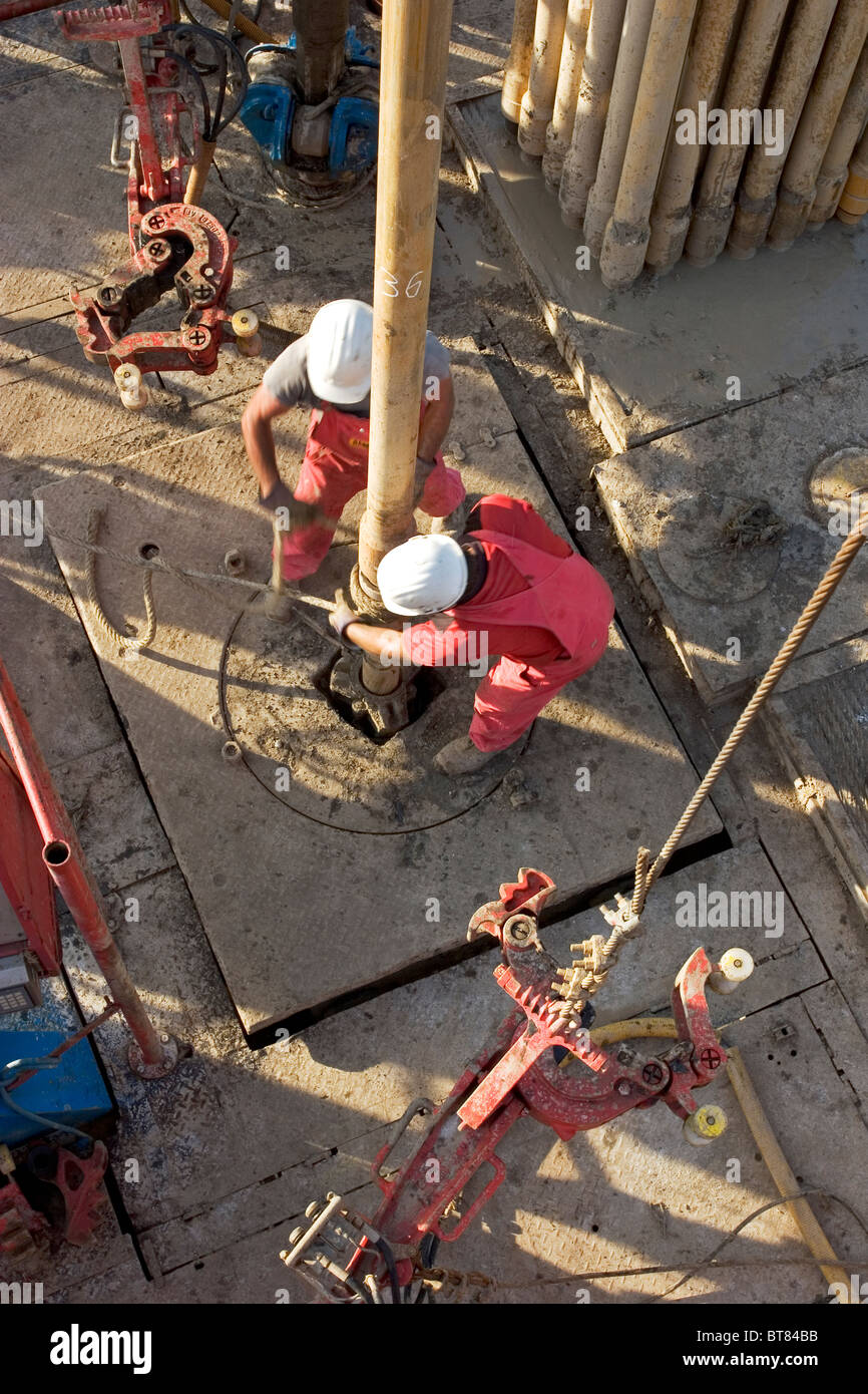 Onshore di esplorazione di petrolio e gas sito rig. Guardando verso il basso sui marinai tubazione di collegamento durante la perforazione. Uganda Foto Stock