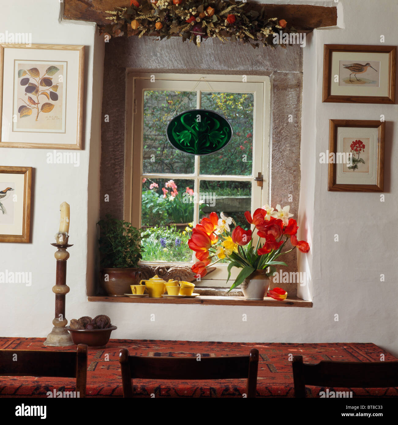Ghirlanda di fiori sulla finestra con vaso di tulipani sul davanzale di  cottage sala da pranzo con vista sul giardino Foto stock - Alamy