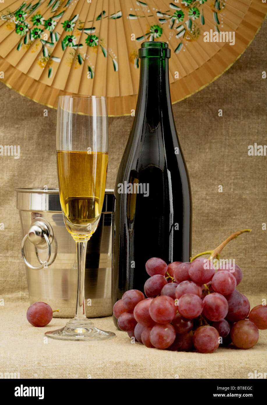 Natura morta con bottiglia di champagne, benna, calice e uva Foto Stock
