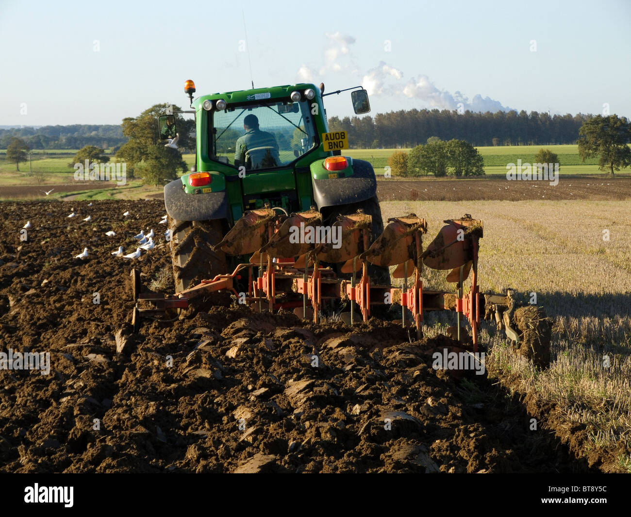 John Deere trattore 6930 arando un campo su una luminosa e soleggiata giornata di ottobre Foto Stock