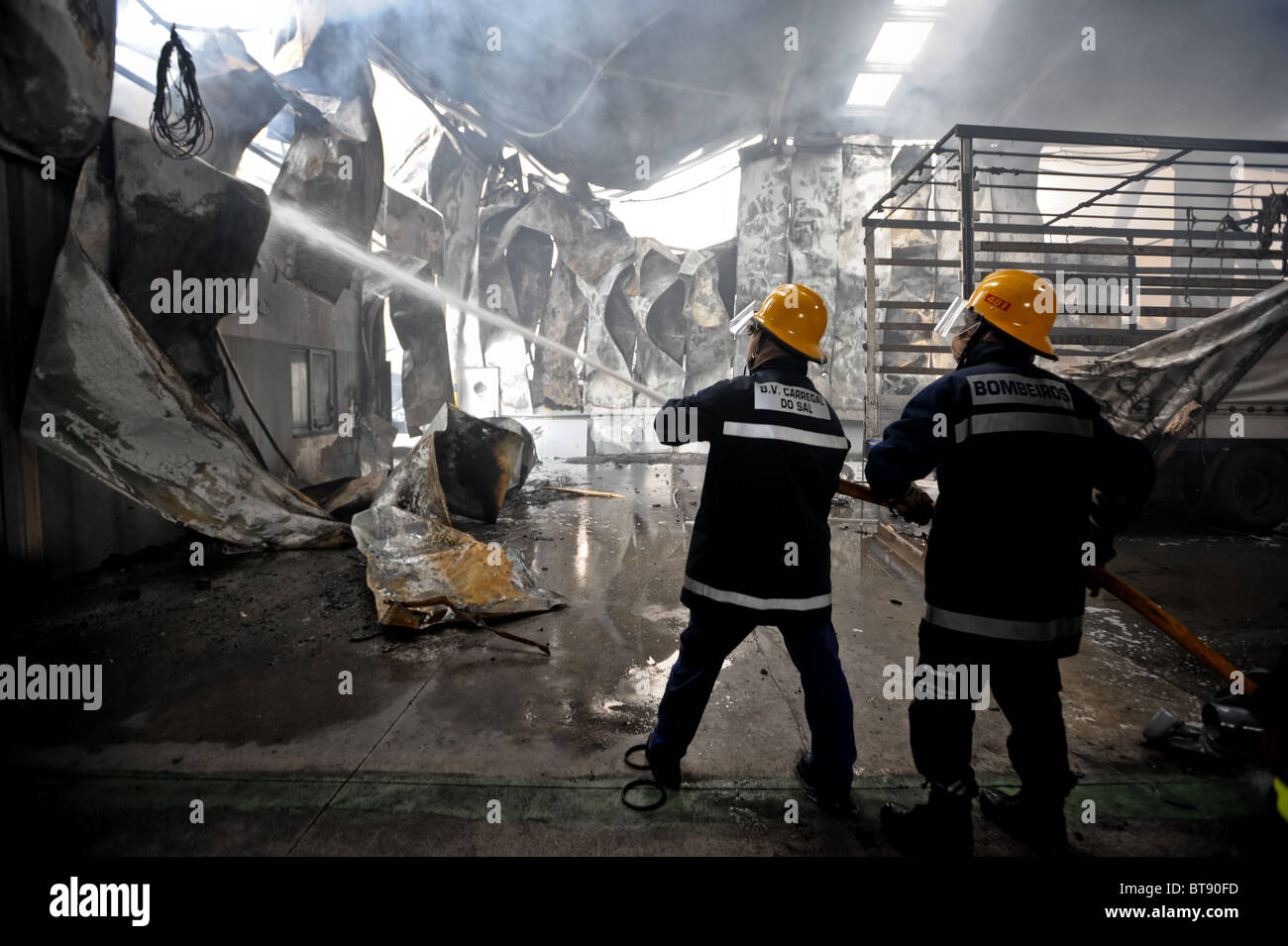 Due vigili del fuoco si aiutano a vicenda durante il combattimento contro un incendio in fabbrica Foto Stock