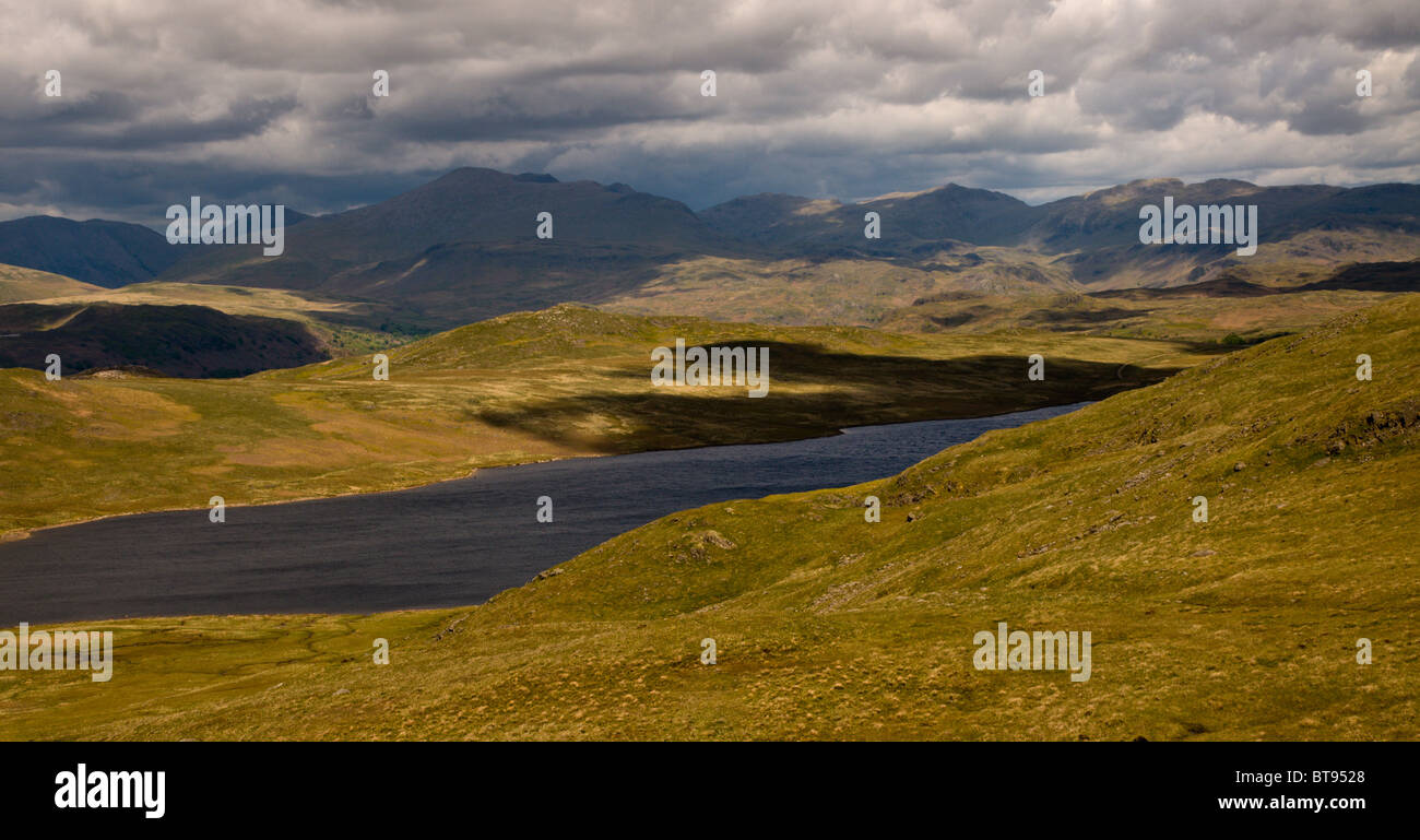 Guardando a nord est attraverso Devoke acqua, un telecomando tarn in Western Lake District, su un triste giorno. Bowfell nella distanza. Foto Stock