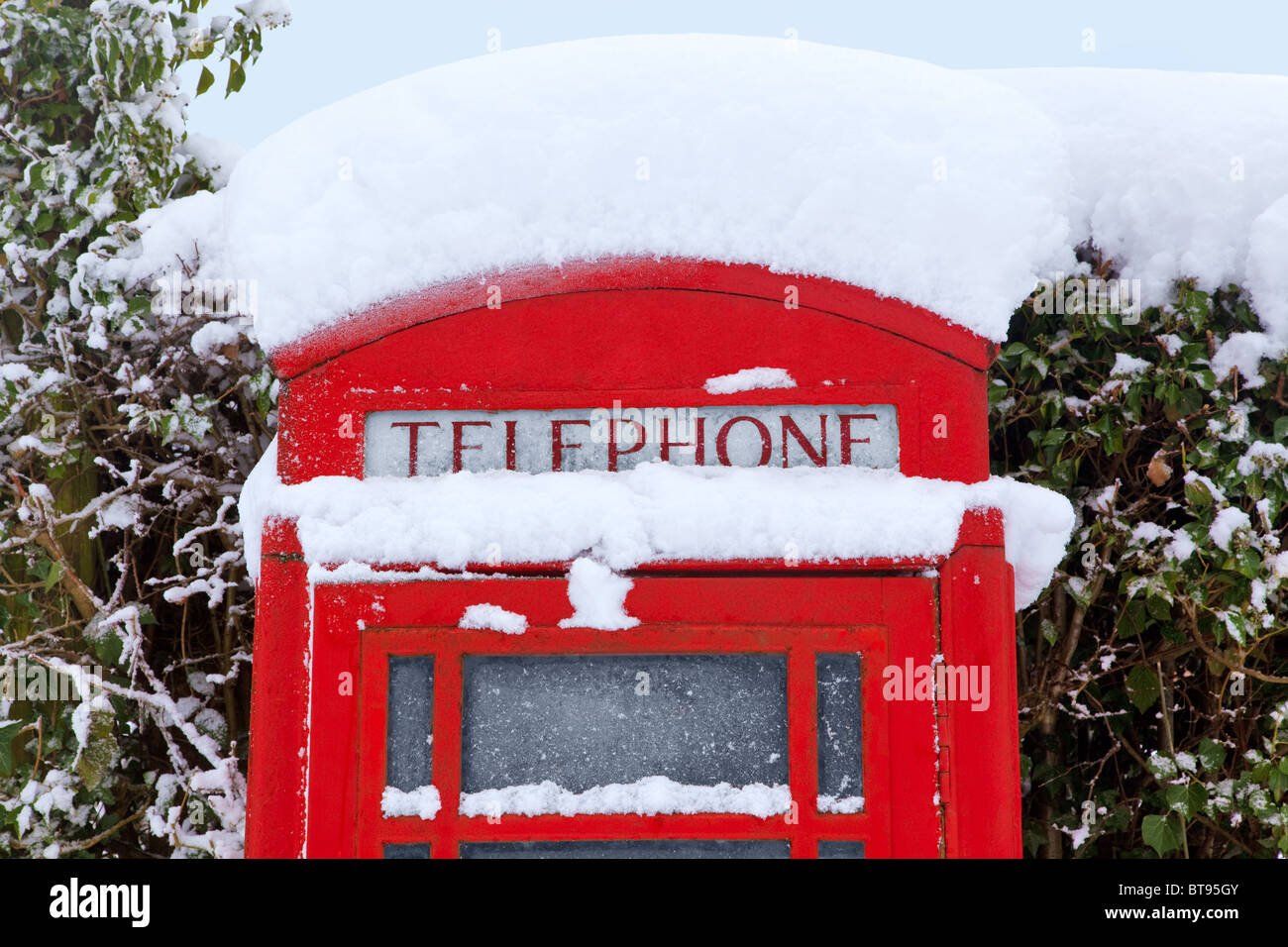 In alto di un tradizionale rosso inglese phonebox coperto di neve. Foto Stock
