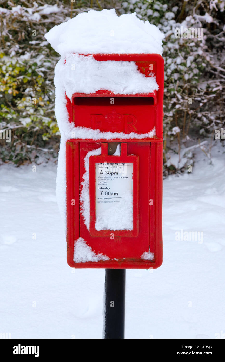 Un rosso tradizionale inglese postbox al tempo invernale coperto di neve. Foto Stock