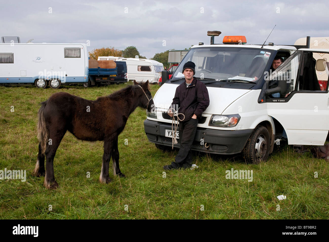 Un giovane viaggiatore irlandese si appoggia sul cofano del suo white pick up truck tenendo il suo piccolo pony a Stow Fiera Cavalli. DAVID MANSELL Foto Stock