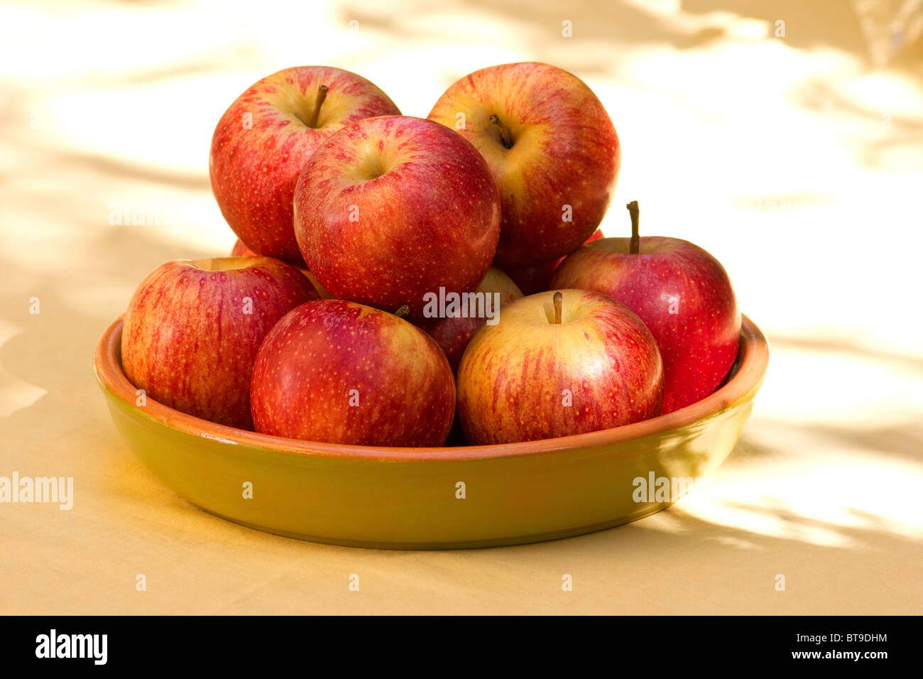 Close-up di mele rosse in una ciotola su sun accesa tabella Foto Stock