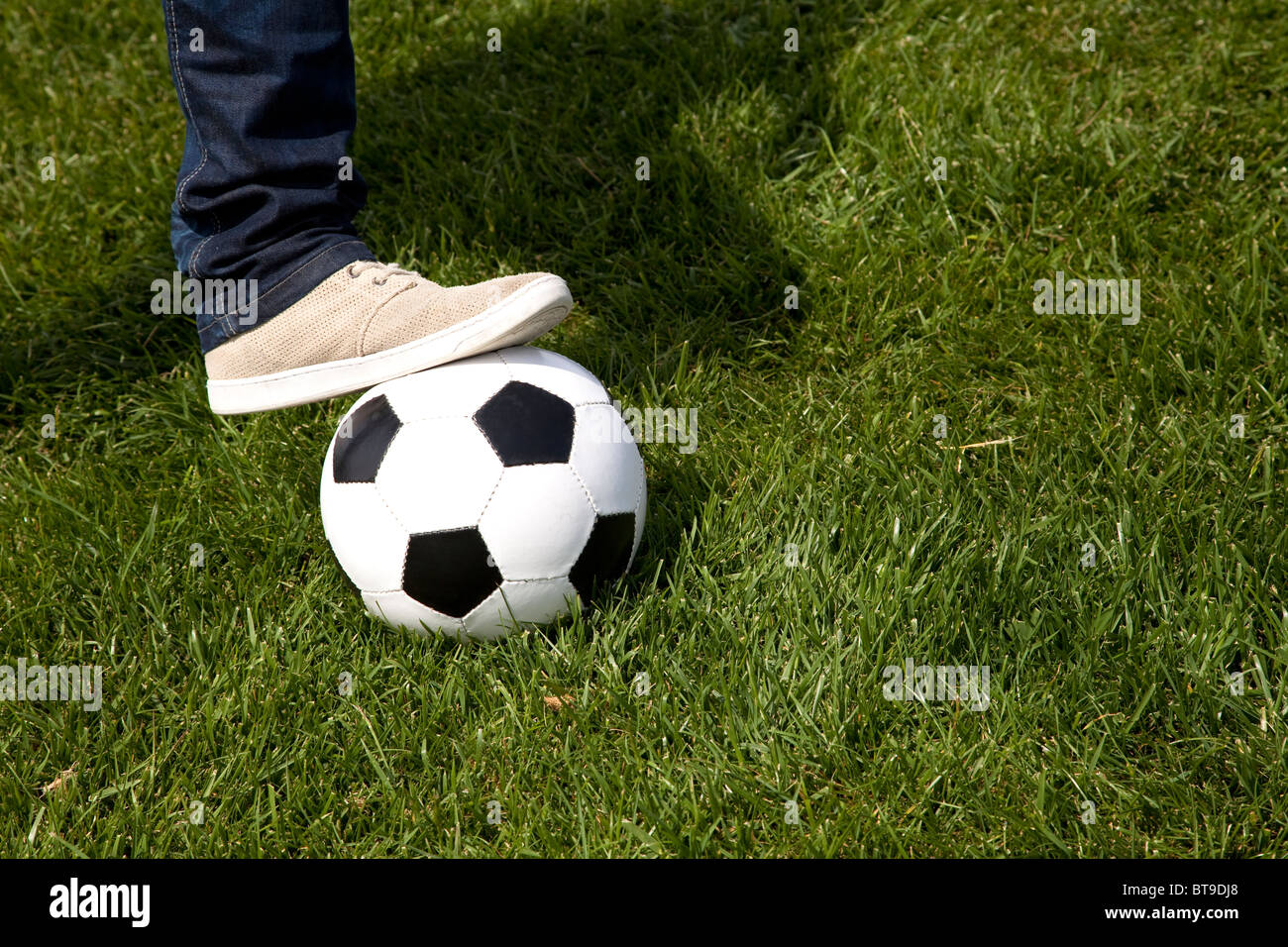Dettaglio di un piede umano su un pallone da calcio in erba Foto Stock