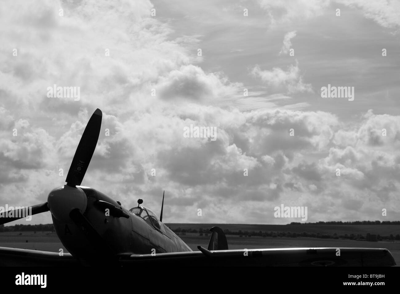 In bianco e nero di studio di un Supermarine Spitfire parcheggiato sotto un grande cielo. Foto Stock