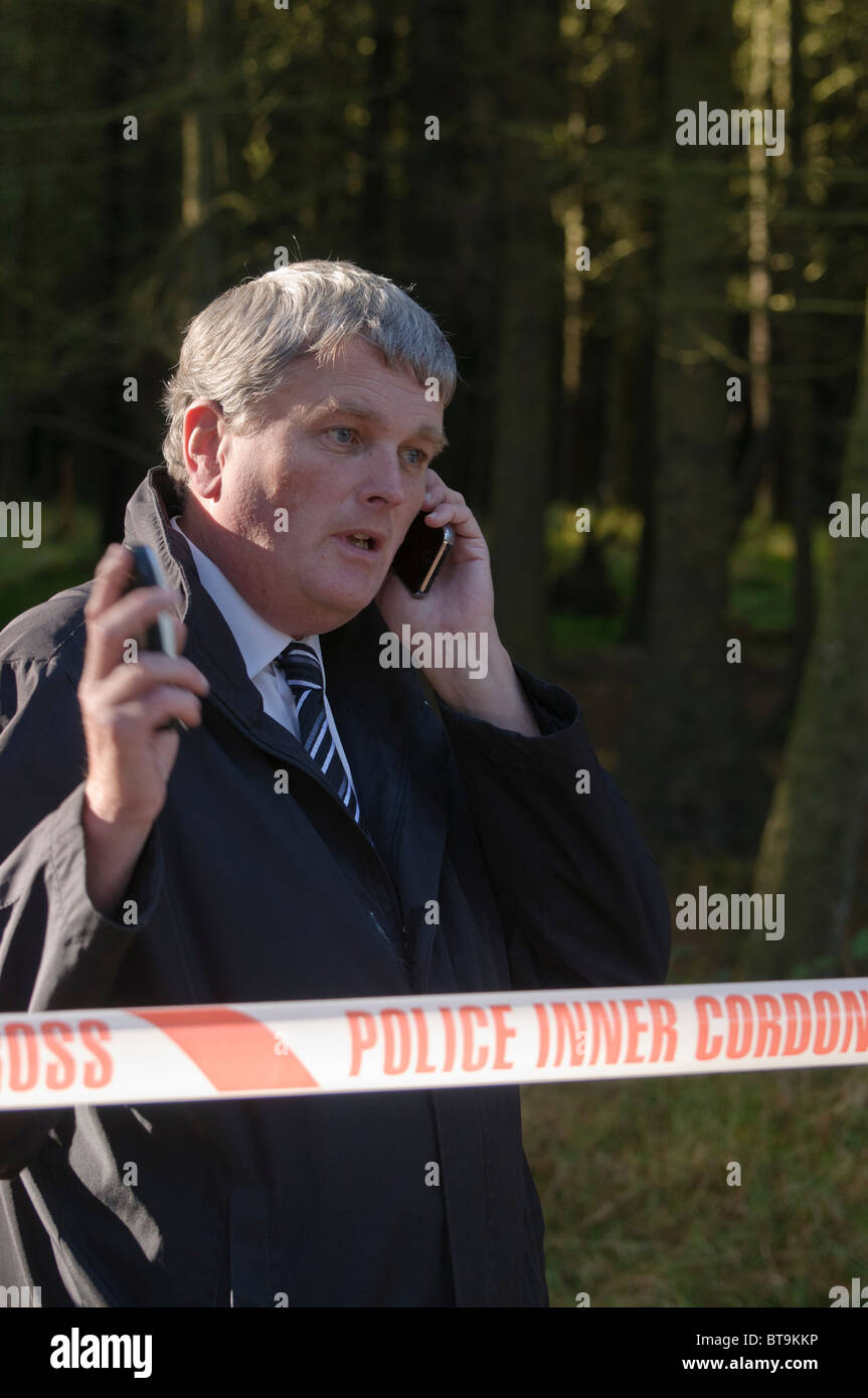 Jim Wells, MLA, (DUP) a parlare su un telefono cellulare mentre in corrispondenza di un cordone di polizia. Foto Stock