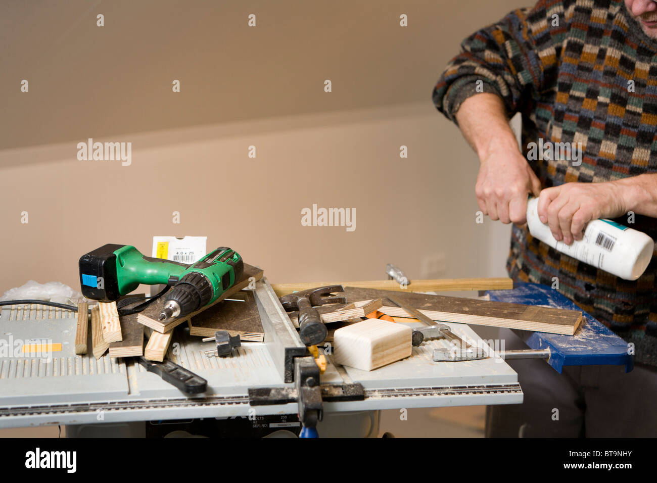 L'uomo con i suoi strumenti per la lavorazione del legno. Egli sta preparando per incollare un pezzo di legno. Foto Stock