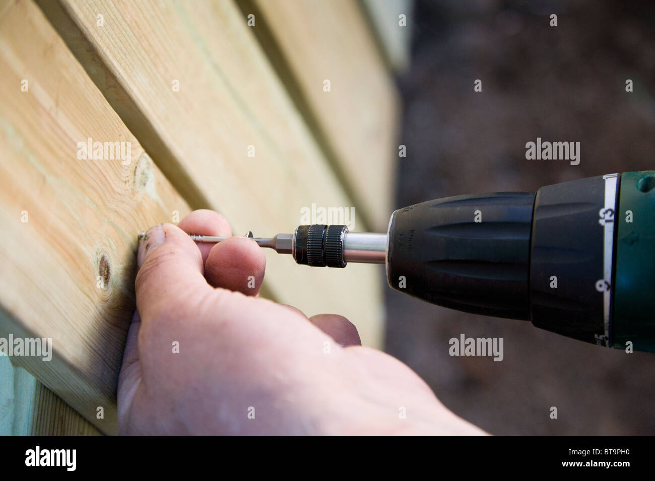 L'uomo costruire una staccionata in legno/parete nel giardino. Foto Stock