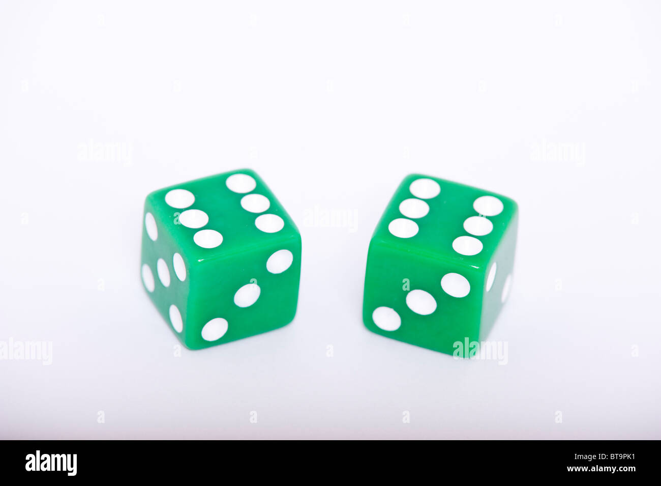 Una coppia di dadi verde sia che mostra un sei su sfondo bianco Foto Stock