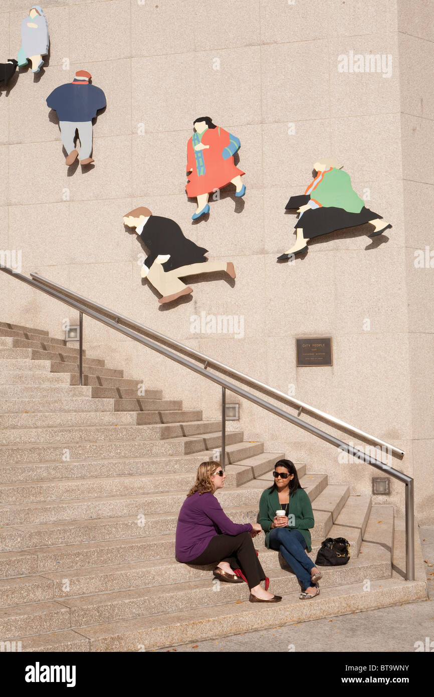 Le donne rilassante sui gradini vicino alla Royal Bank of Canada su Front Street, Toronto. Dietro è "Gente di città' da Caterina Widgery Foto Stock