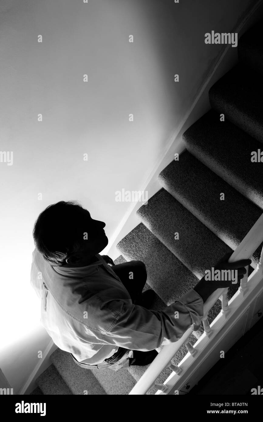 Uomo che cammina al piano di sopra, pesanti ombre. Bianco & nero Foto Stock
