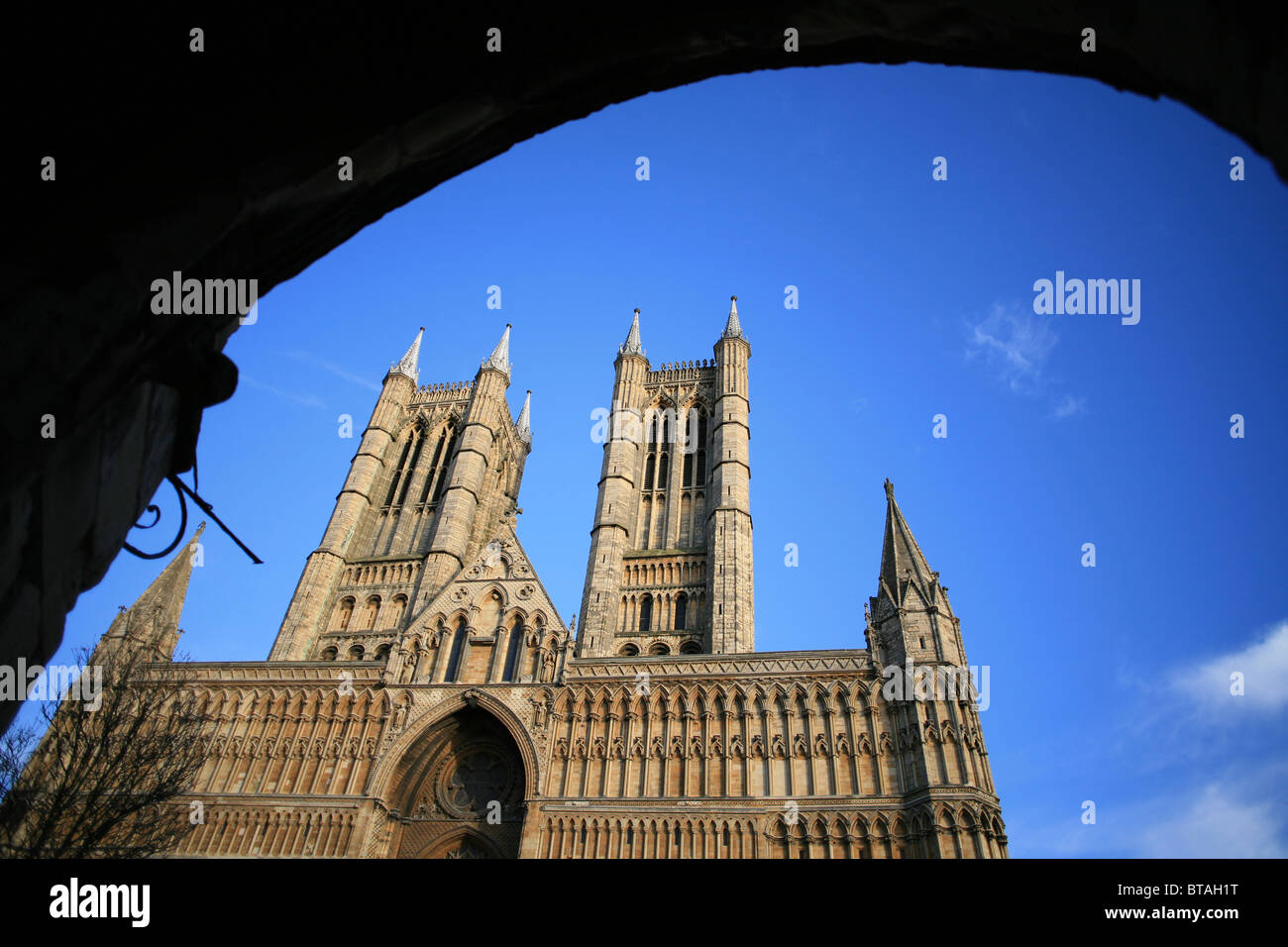 Le imponenti torri e fronte ovest della Cattedrale di Lincoln visto attraverso la porta del Tesoro. Foto Stock