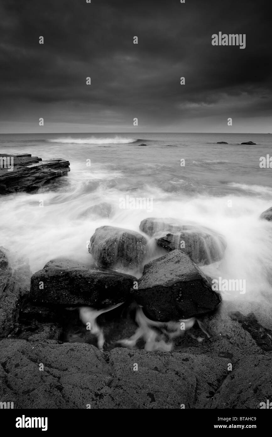 Onde di oltre le rocce con la bassa marea, Saltwick Bay vicino a Whitby, North Yorkshire Coast Foto Stock