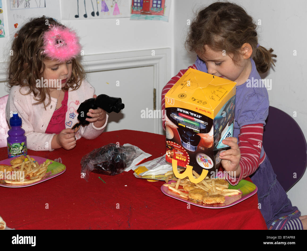 Sorelle avente un Mcdonald's Happy Meal giocando con Star Wars giocattoli Inghilterra Foto Stock