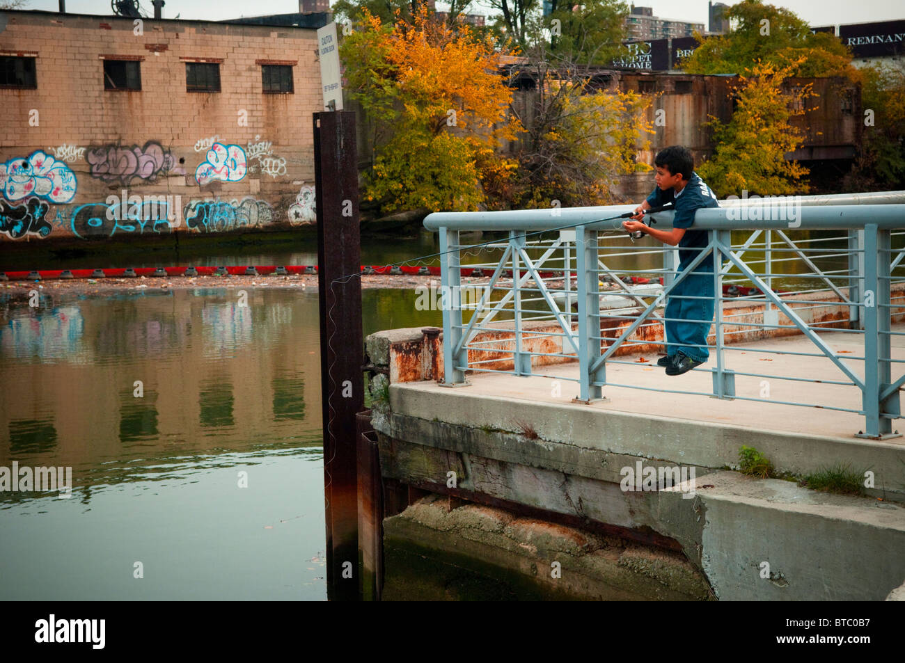 Un ragazzo pesci ad impianto di calcestruzzo parco lungo il fiume Bronx in New York borough del Bronx Foto Stock