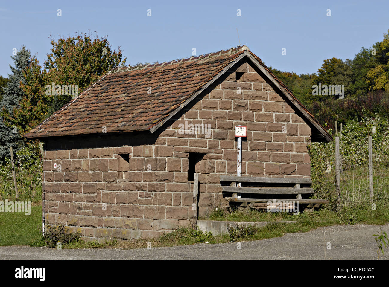 Piccola casa in pietra con panca di legno Foto Stock