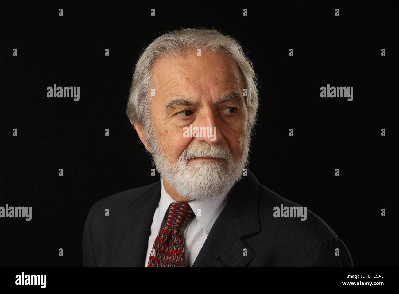 Ritratto di barba e capelli grigi imprenditore senior in tuta e cravatta, studio shot sfondo nero, 16 Ottobre 2010 Foto Stock