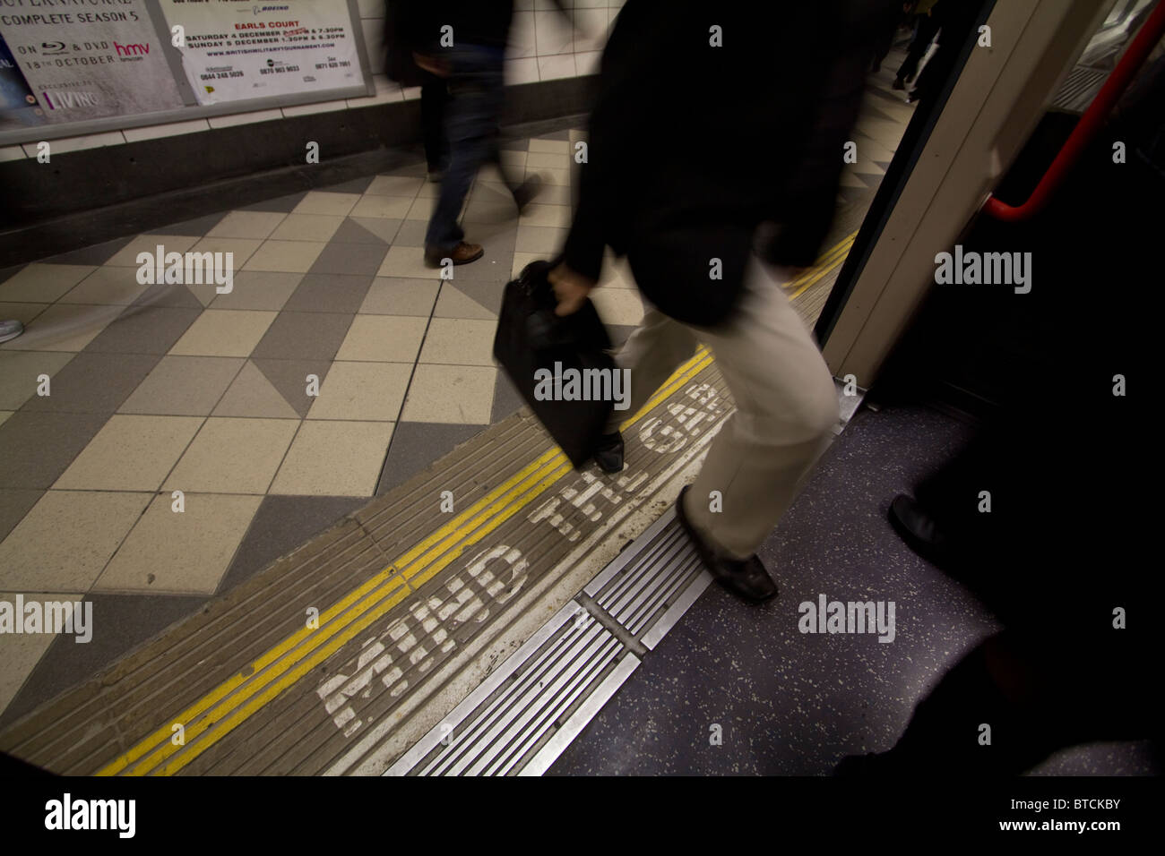 Il passeggero di salire sulla metropolitana di Londra il treno sul tubo di rete, con la mente il divario segno sulla piattaforma Foto Stock