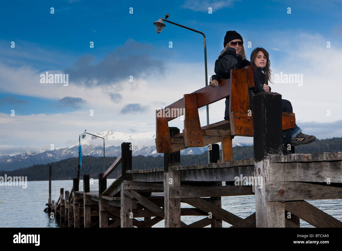 Due donne seduta su una panchina in un molo a Bahia Manzano, Villa La Angostura, Patagonia Argentina sul Lago Nahuel Huapi Foto Stock