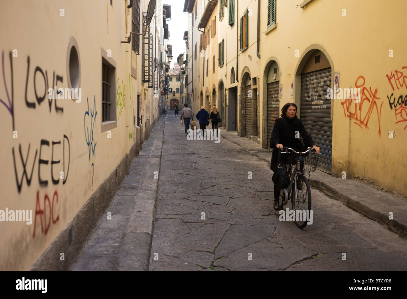 Italian ciclista pedala lungo graffiti street vicino a Firenze Piazza Santa Croce. Foto Stock