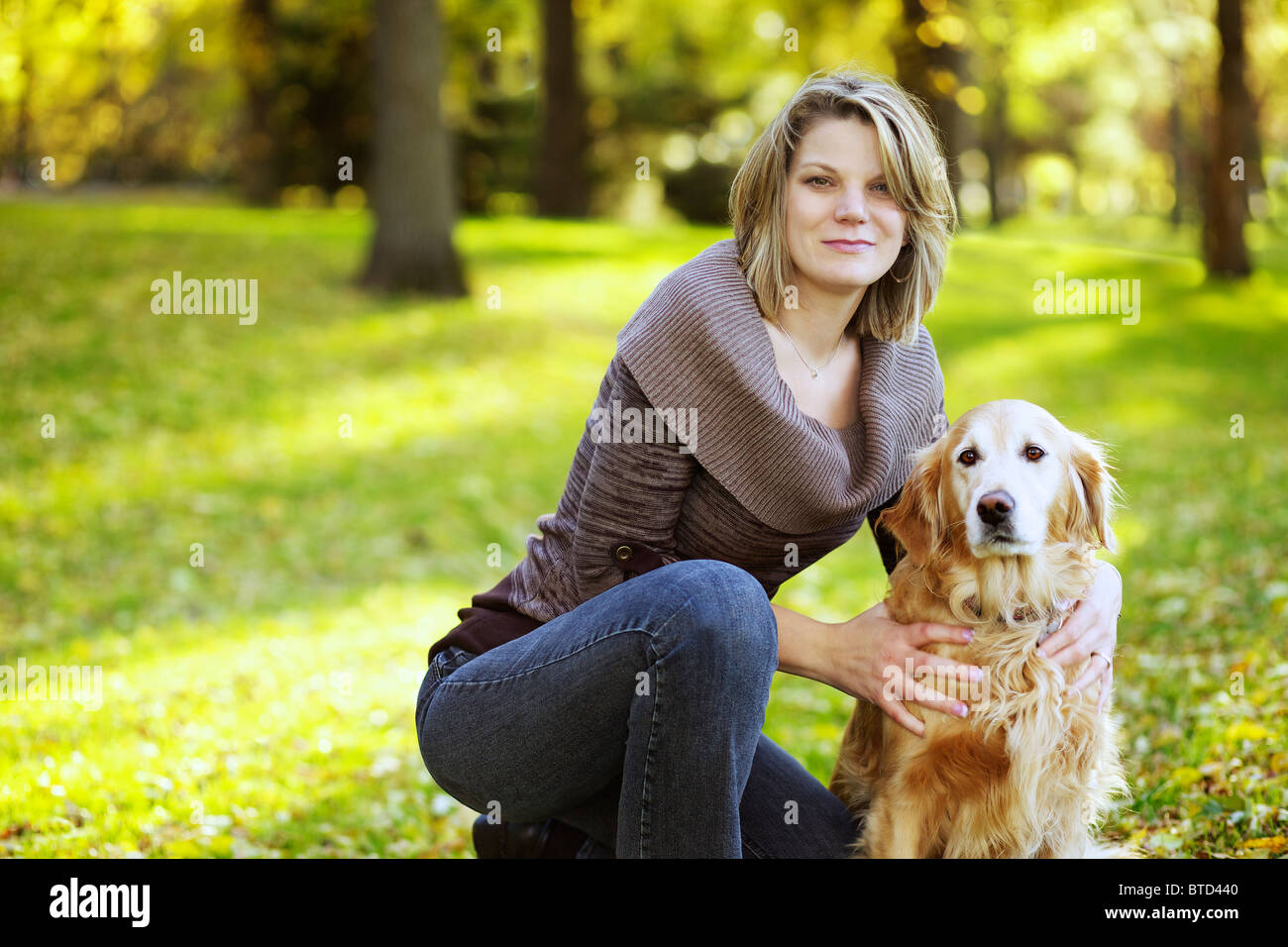 Ritratto di una bella donna caucasica con il suo golden retriever cane al parco Foto Stock
