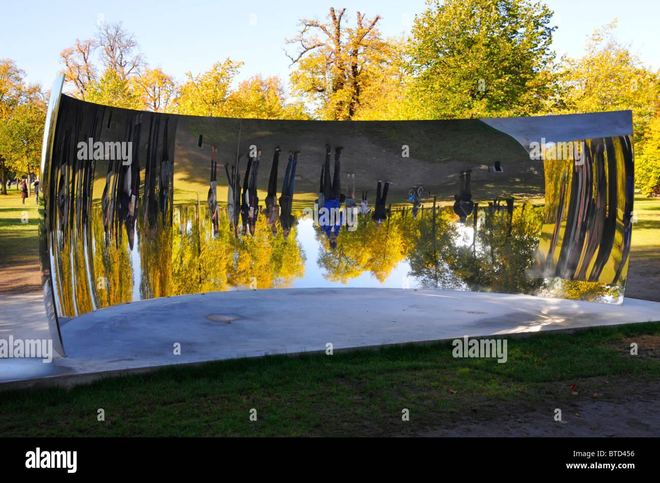 I turisti che visitano i Kensington Gardens hanno visto immagini riflesse di se stessi in uno degli specchi Anish Kapoor Sky Mirrors C Curve London Inghilterra UK Foto Stock