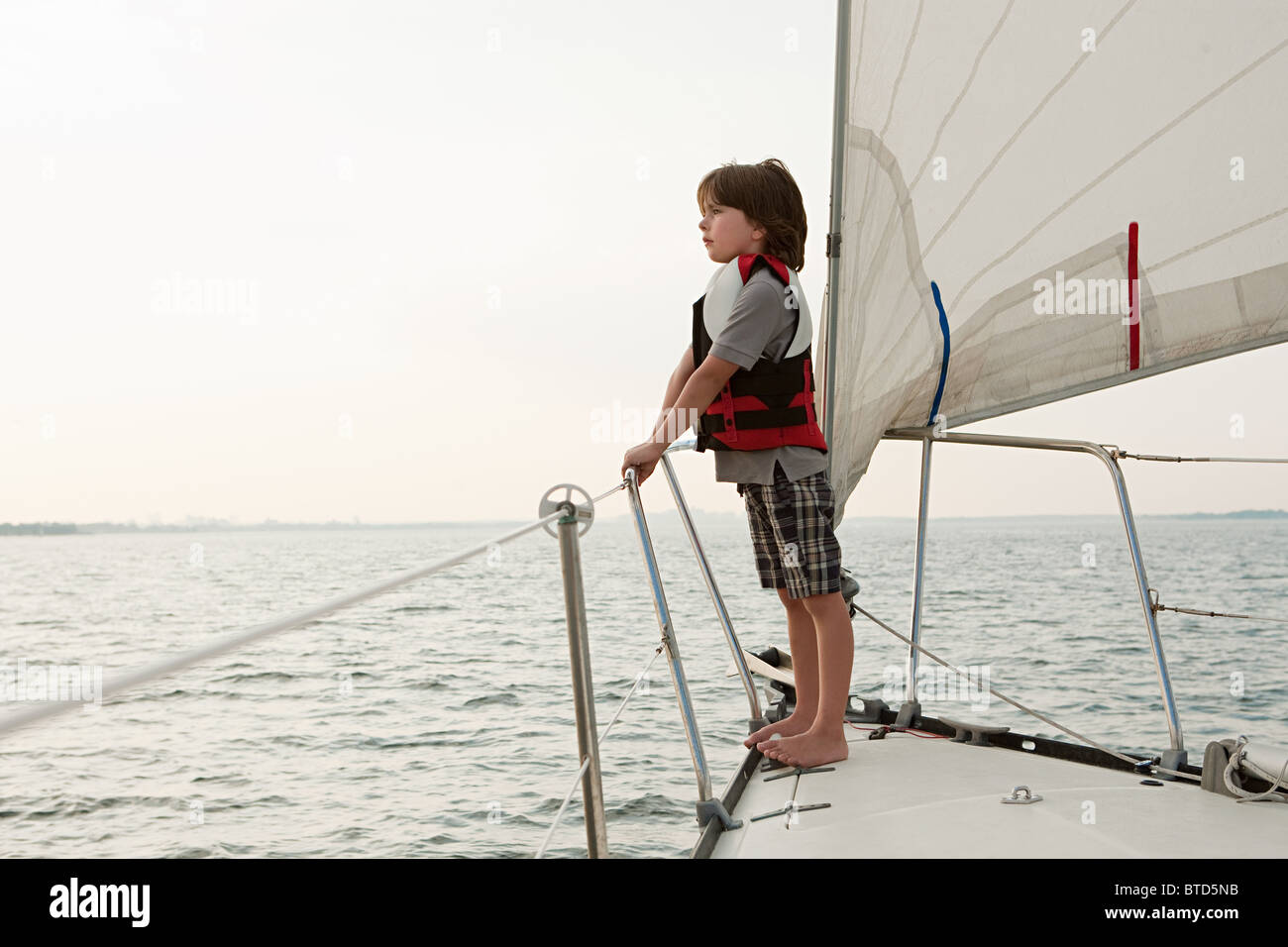 Ragazzo giovane a bordo di yacht, guardando a vista Foto Stock