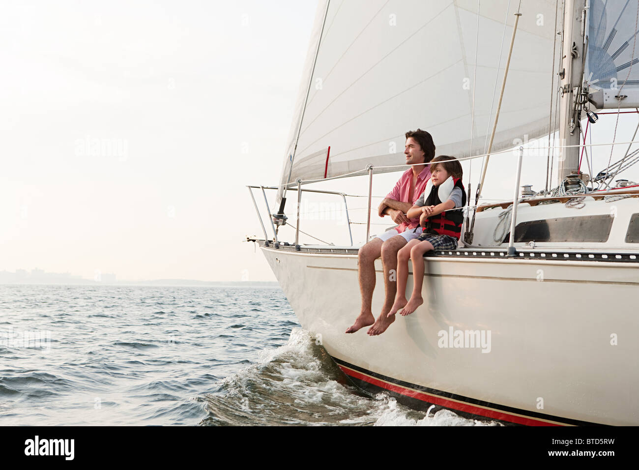 Padre e figlio seduti su yacht Foto Stock