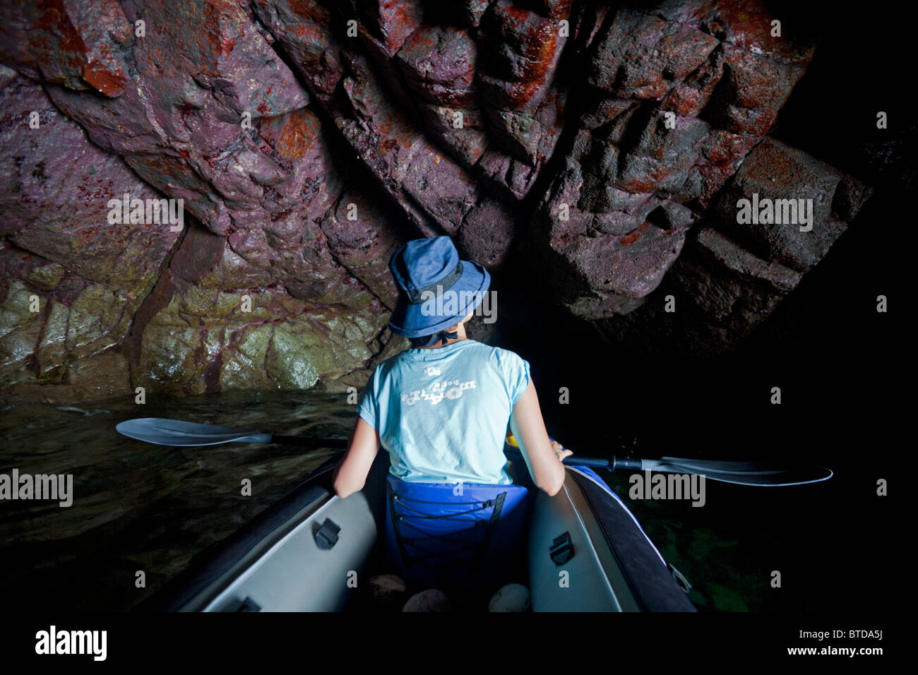 Una giovane donna di esplorare una grotta marina della penisola di Crozon (Bretagna). Jeune femme explorant une grotte marine de Morgat. Foto Stock