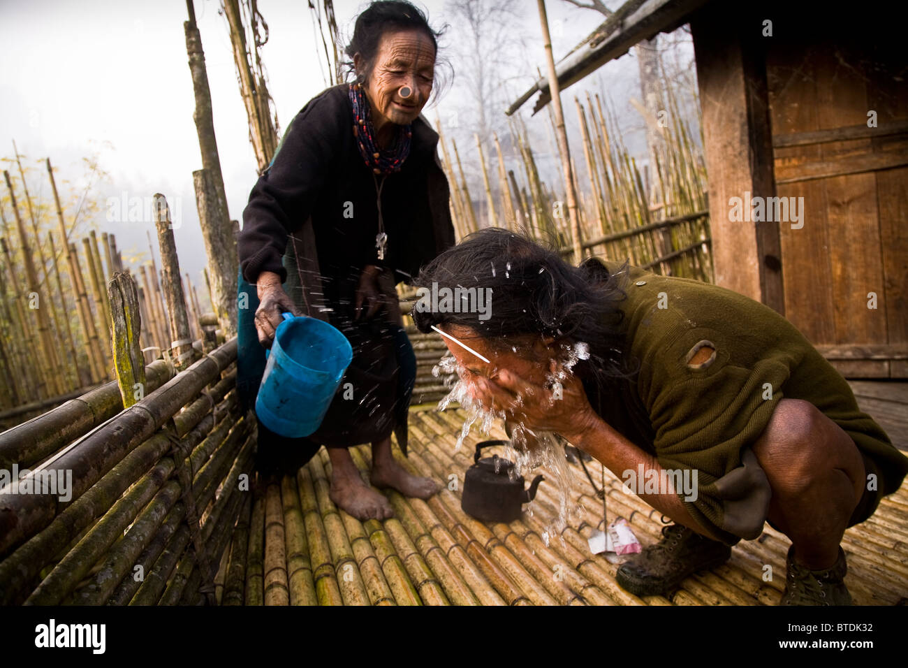 Apatani gli anziani delle tribù Atta Yadd e suo marito Ba Khang svegliarsi la mattina presto, rinfrescarsi sul sopraelevato piattaforma di bambù Foto Stock