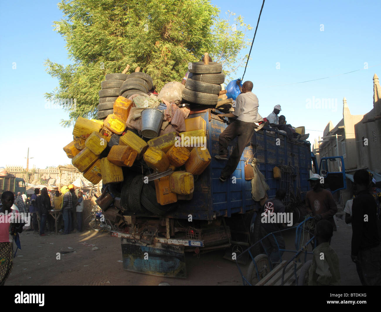 Un carrello sovraccaricato con pneumatici e bottiglie di plastica di guida attraverso un villaggio Foto Stock