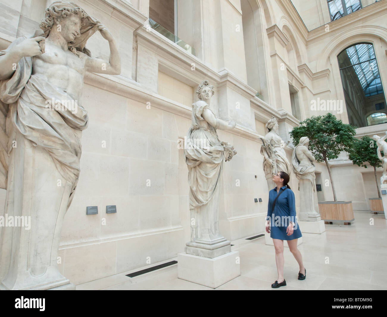 Donna che guarda le sculture al museo del Louvre a Parigi Francia Foto Stock