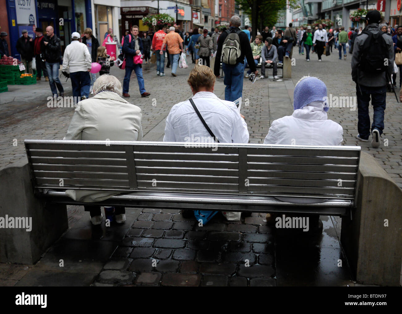 Tre signore seduto su Market Street nel centro della città di Manchester REGNO UNITO Foto Stock