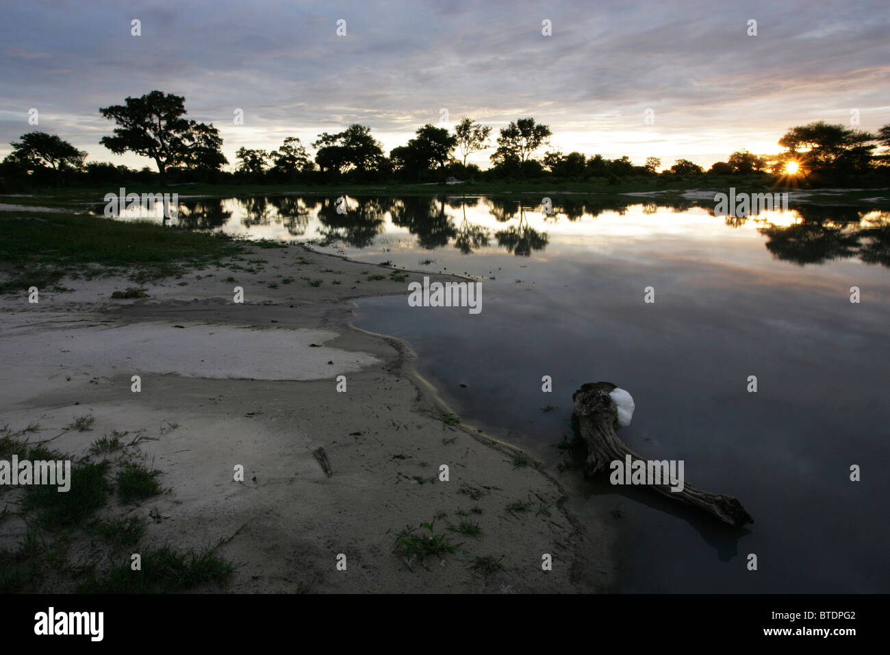 Tramonto su l'Okavango da una riva sabbiosa Foto Stock