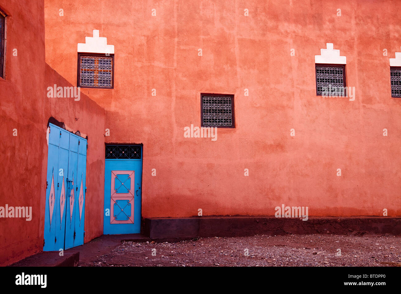 Una luce arancione brillante Berber Kasbah con due porte blu Foto Stock
