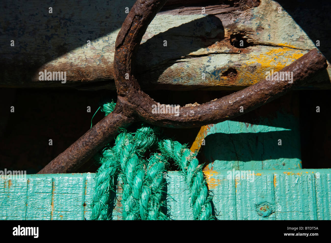 La corda e il dispositivo di ancoraggio che giace contro di legno verde lato della barca Foto Stock