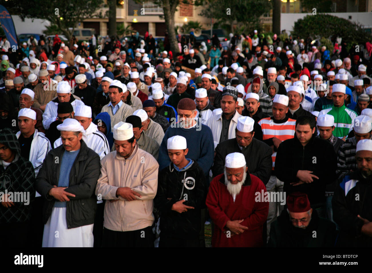 Uomini musulmani indossando tappi di preghiera pregare prima del primo avvistamento della luna a significare la fine del digiuno del Ramadan Foto Stock