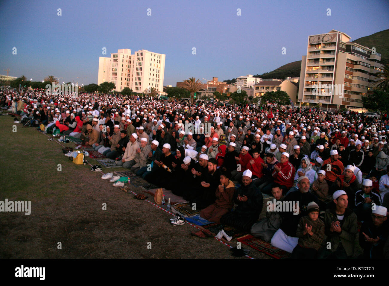 Uomini musulmani inginocchiati su una spiaggia in preghiera davanti al primo avvistamento della luna, a significare la fine del digiuno del Ramadan Foto Stock