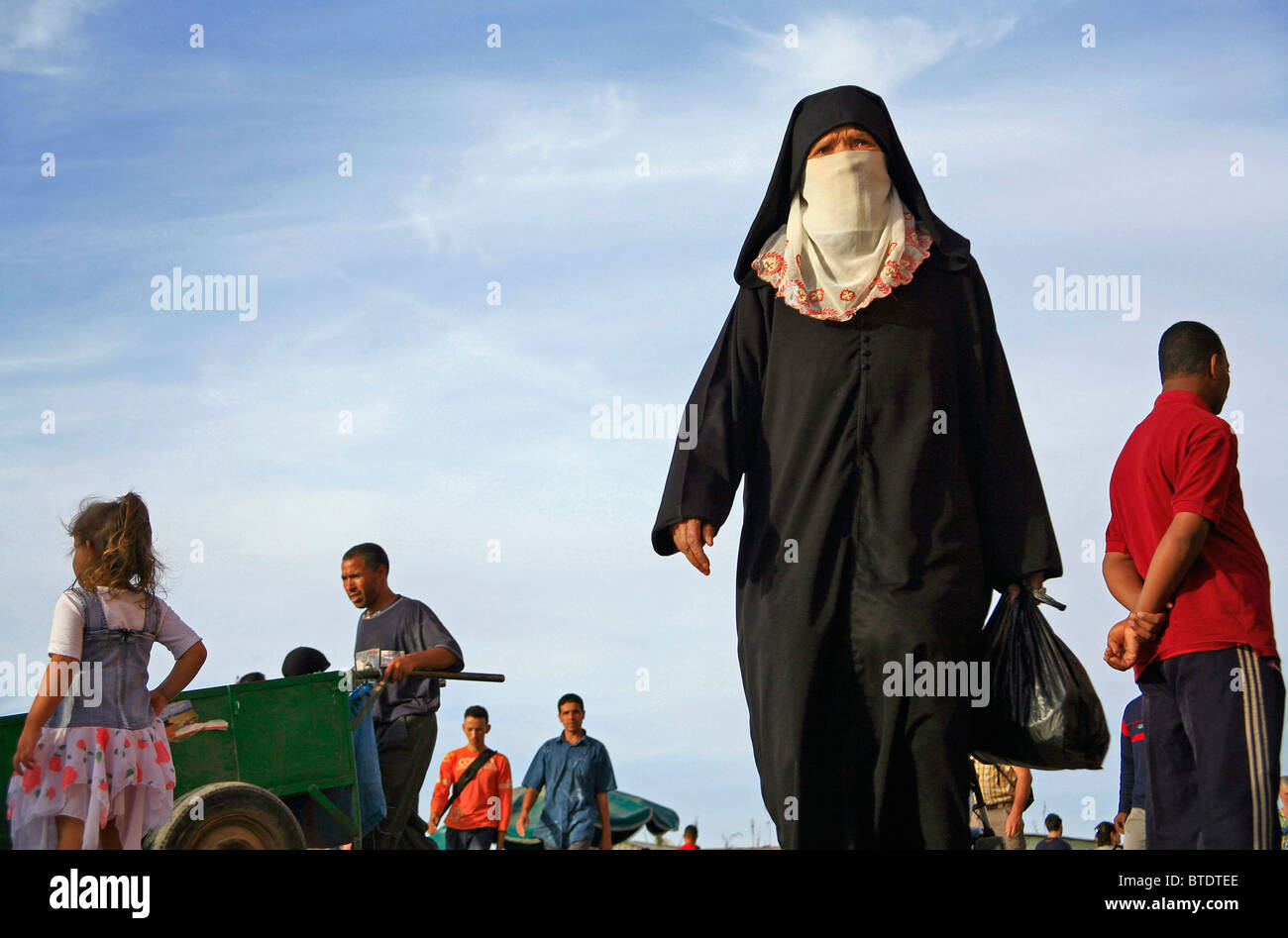 Donna musulmana vestito in un burka camminando in Djemaa el Fna Foto Stock