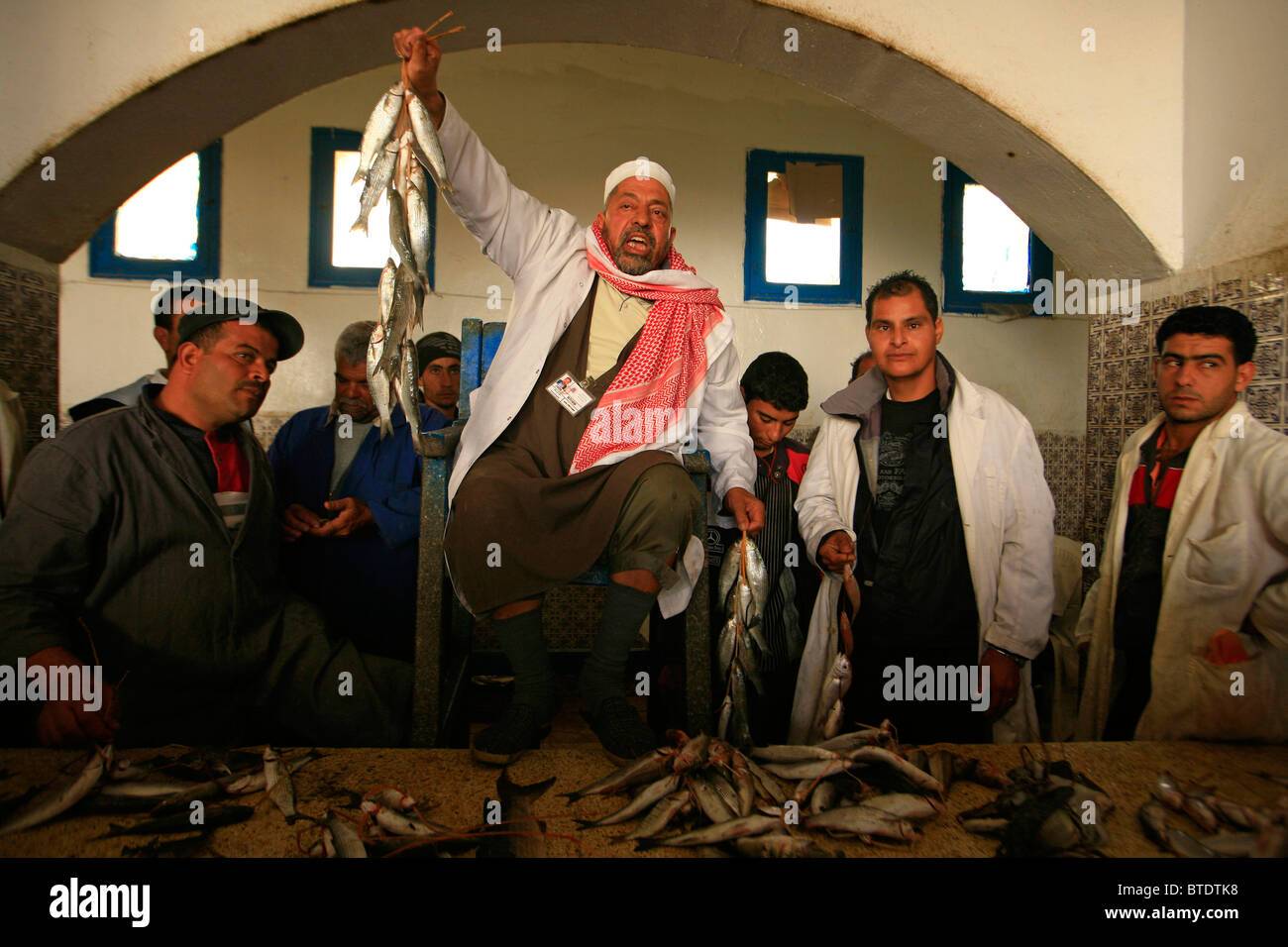 La quotidiana asta del pesce con il banditore tenendo il pesce Foto Stock