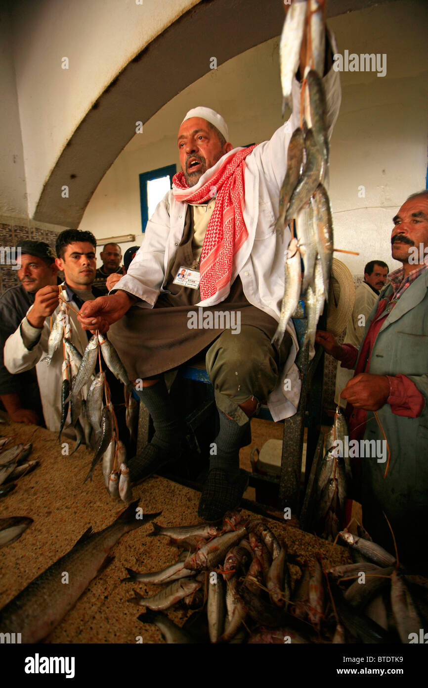 La quotidiana asta del pesce con il banditore tenendo il pesce Foto Stock