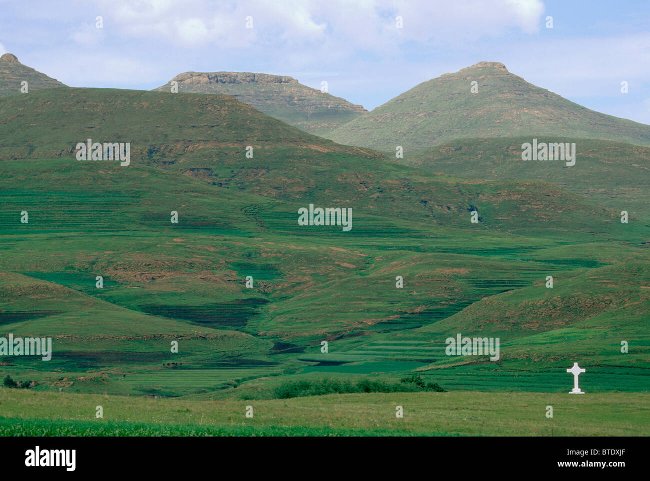 Una croce bianca segna un grave alla base delle montagne Foto Stock