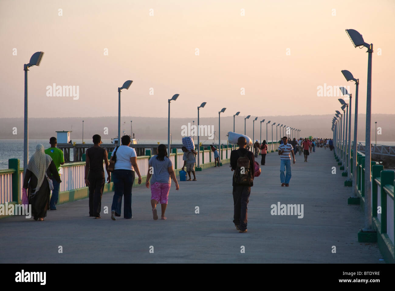 Un mix di turisti e di gente del posto a piedi lungo il molo al Inhambane Foto Stock