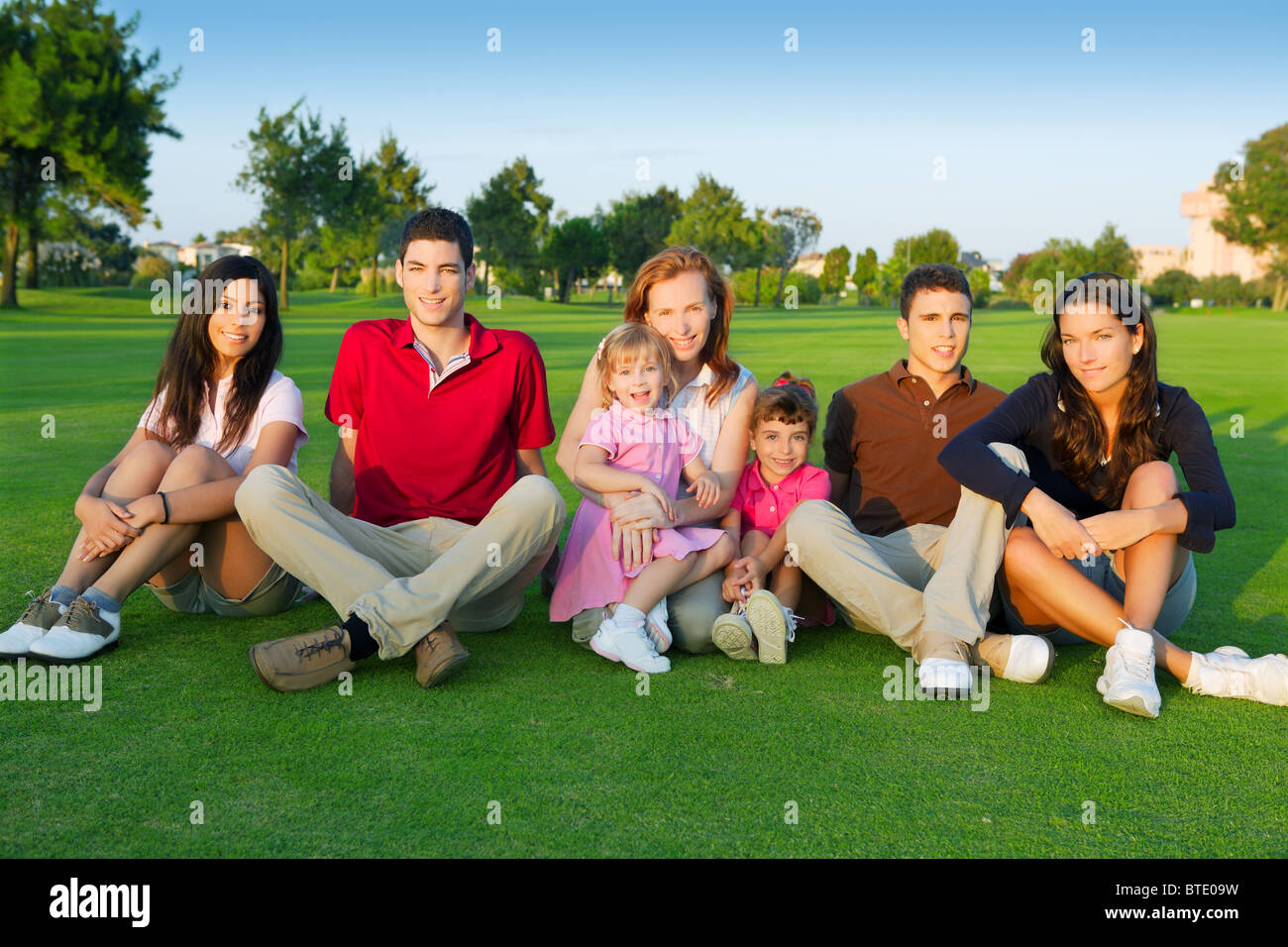 Amici di famiglia gruppo gente seduta erba verde all'aperto con i bambini Foto Stock