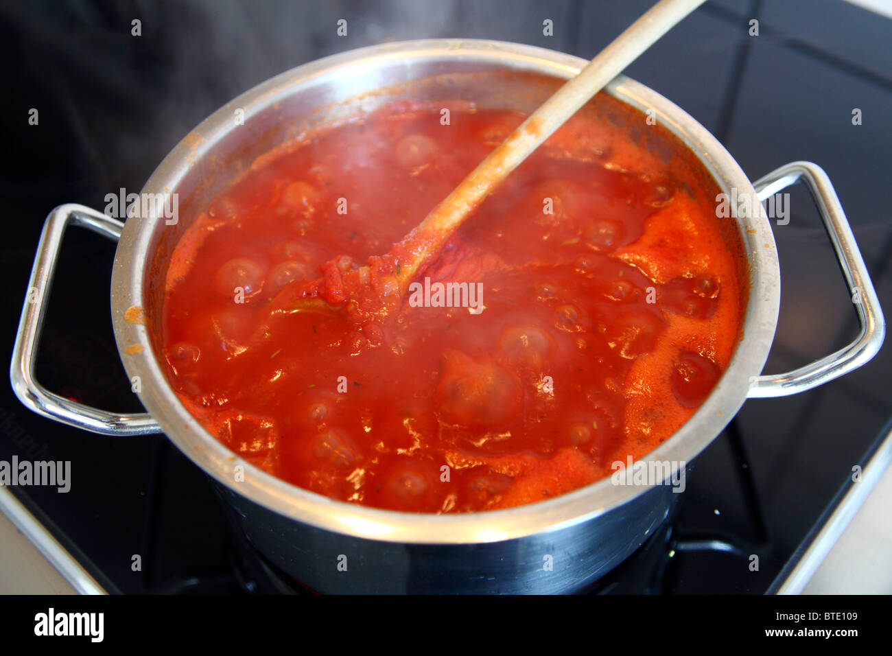 Recipiente di cottura con punto di ebollizione la salsa di pomodoro in un forno elettrico. Foto Stock