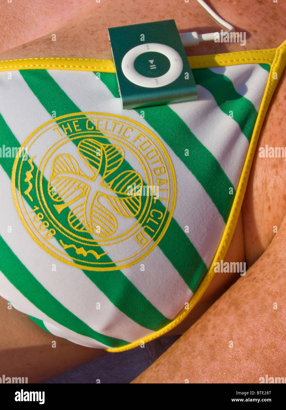 Messa a fuoco selettiva immagine dettagliata di una donna che indossa un CELTIC FOOTBALL CLUB BIKINI E ASCOLTO DI IPOD Foto Stock