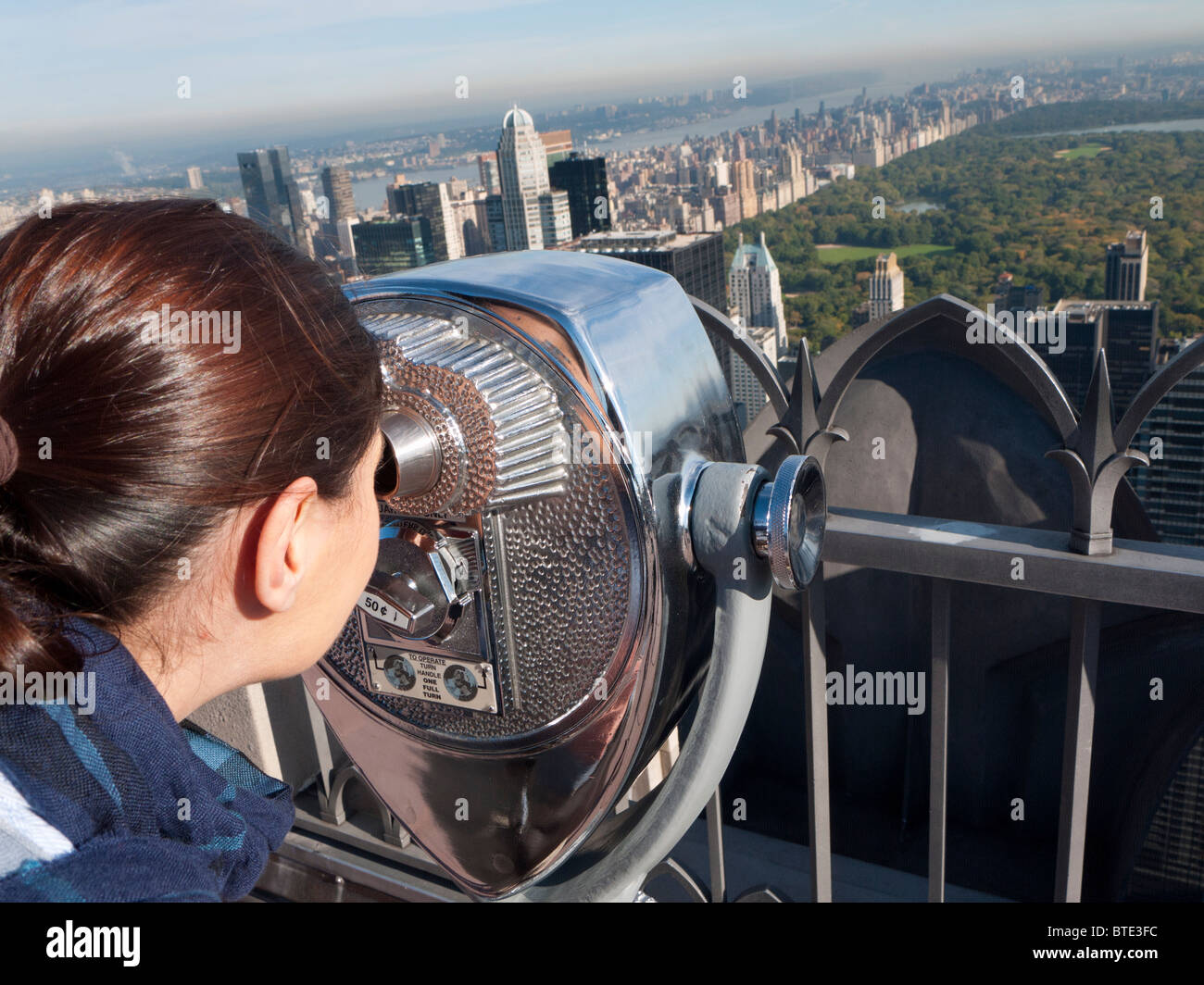 Donna che guarda al Central Park da a gettone binocolo sulla sommità della roccia al Rockefeller Center di Manhattan a New York Foto Stock